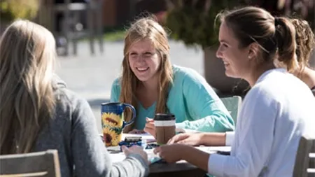 Female students studying at outdoor table on a patio.