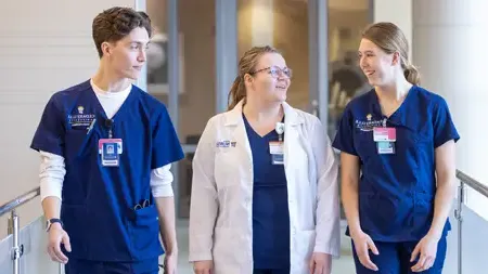 Female faculty discussing something with two nursing students.